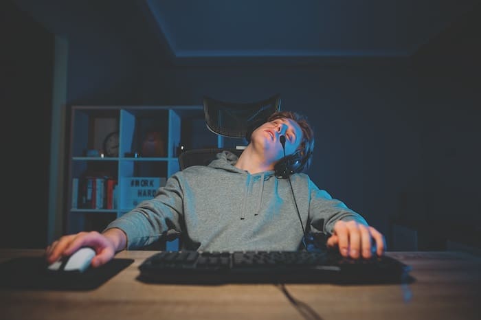Tired gamer sits at home at the computer and sleeps. Dream Interpretation Young man fell asleep while playing on the computer.