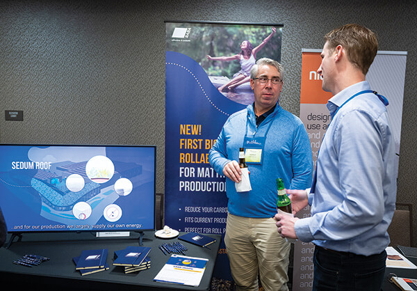 Andy Schaaf of SABA Adhesives talks with a conference attendee about its new biobased rollable adhesive during the kick-off reception.