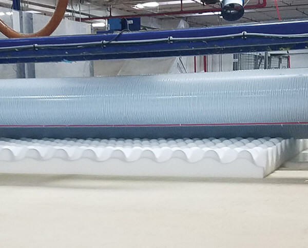 A roll-coat machine applies Worthen Industries Inc.’s FoamLam lamination adhesive to a convoluted foam.