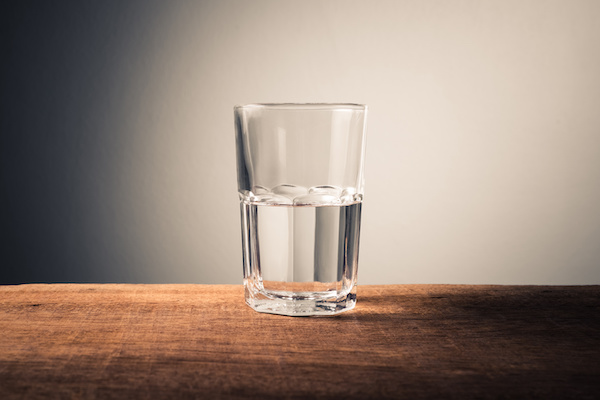 Glass of water with half full water on the table, concept of positive and negative thinking