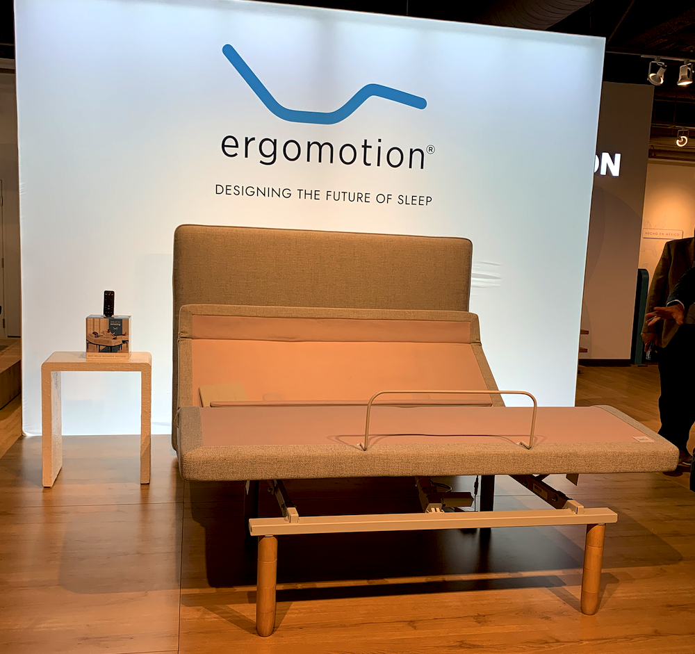 Ergomotion elevated an articulated flagship model on a well-lit platform and backed it with a simple “Designing the Future of Sleep” message. 