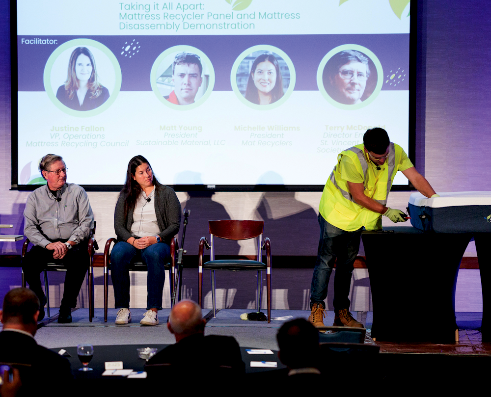 Matt Young, president of Sustainable Material LLC, takes a knife to a mattress onstage to show what recyclers encounter when deconstructing a mattress for recycling while panelists
and fellow recyclers Terry McDonald and Michelle Williams, look on.
