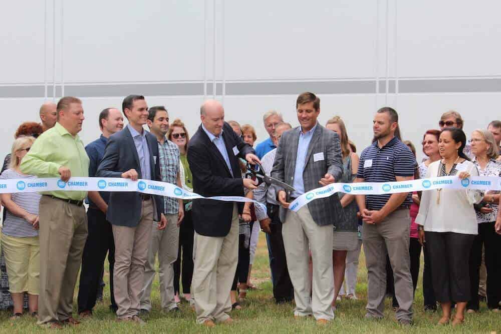 Brandon Wells, BekaertDeslee USA general manager, cuts the ribbon on a new warehouse at the Winston-Salem, North Carolina, company headquarters. He is flanked by Mark Owens, Winston-Salem Chamber of Commerce president and chief executive officer, as well as other invited guests and employees.