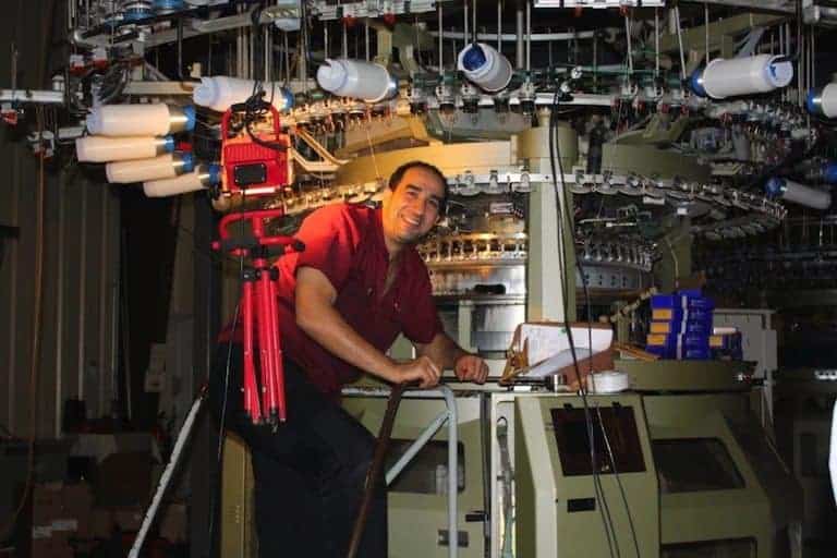 Knitting technician Farid Kassmi poses in front of a circular knitting machine at DesleeClama
