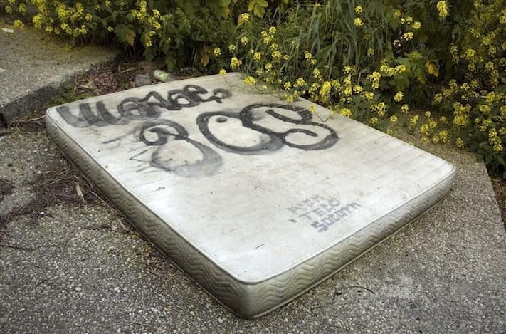 improperly discarded mattress with graffiti