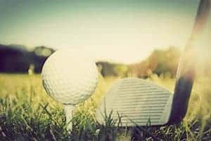 Golf ball on white tee and golf club preparing to shot.