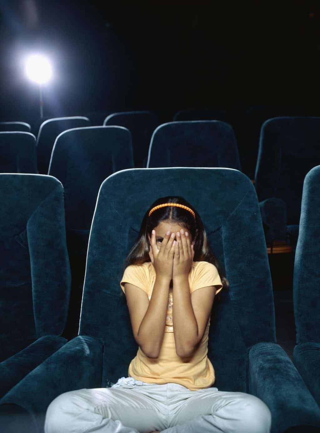 girl covering her face at scary movie
